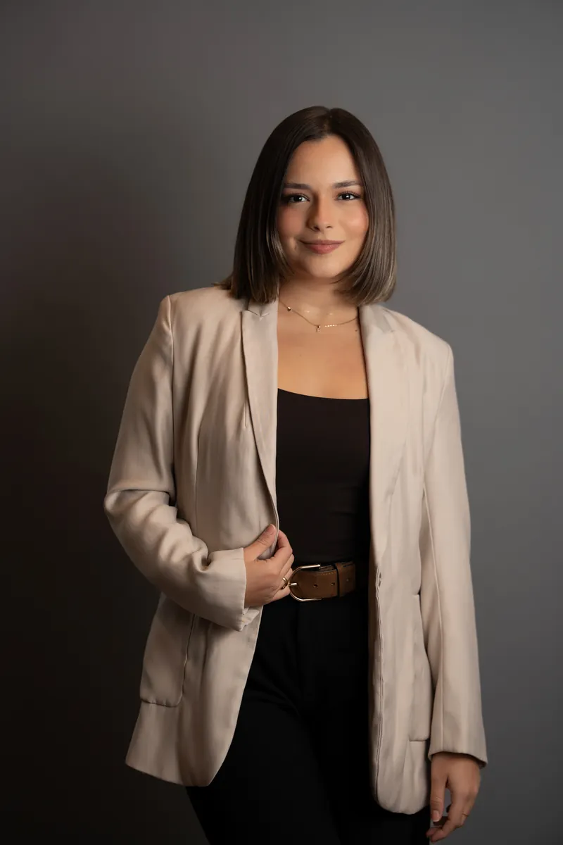 Professional headshot of woman in black blazer adjusting jacket