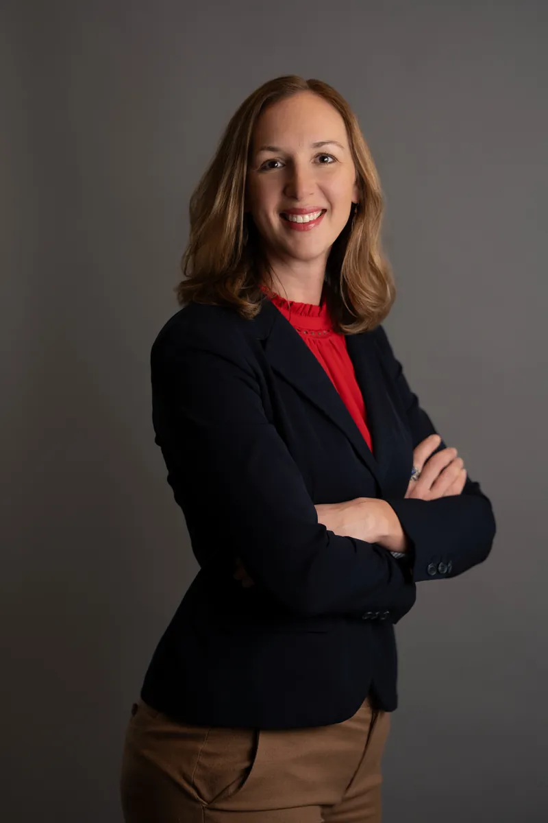 Professional headshot of woman in navy blazer with red blouse