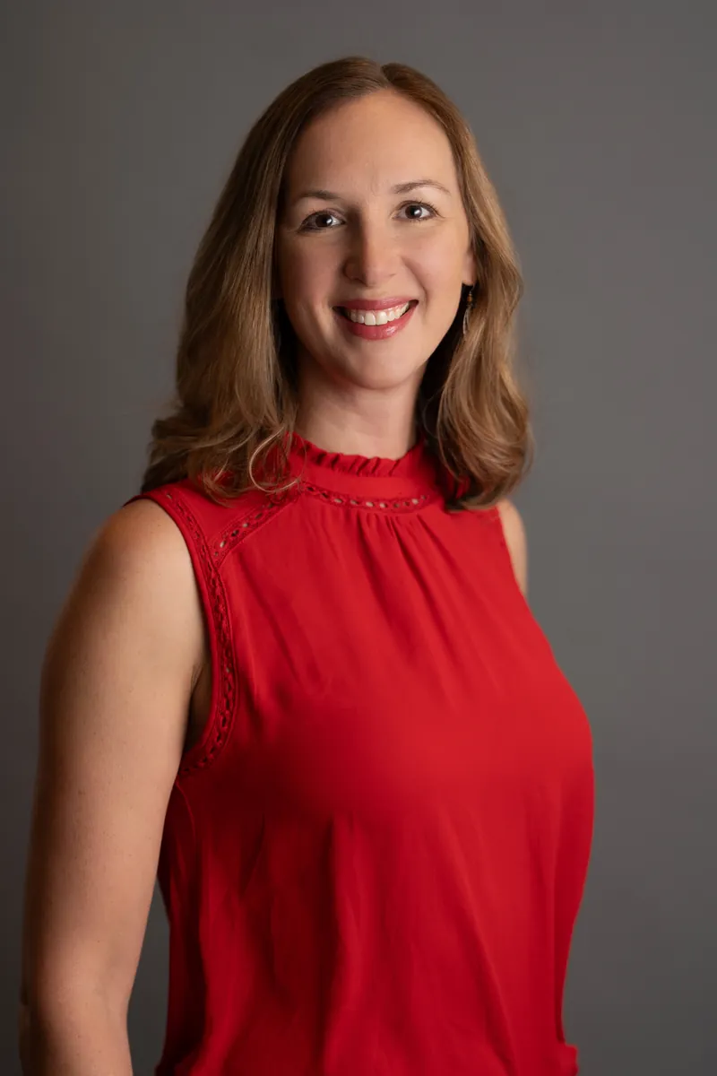 Professional headshot of woman in red sleeveless top