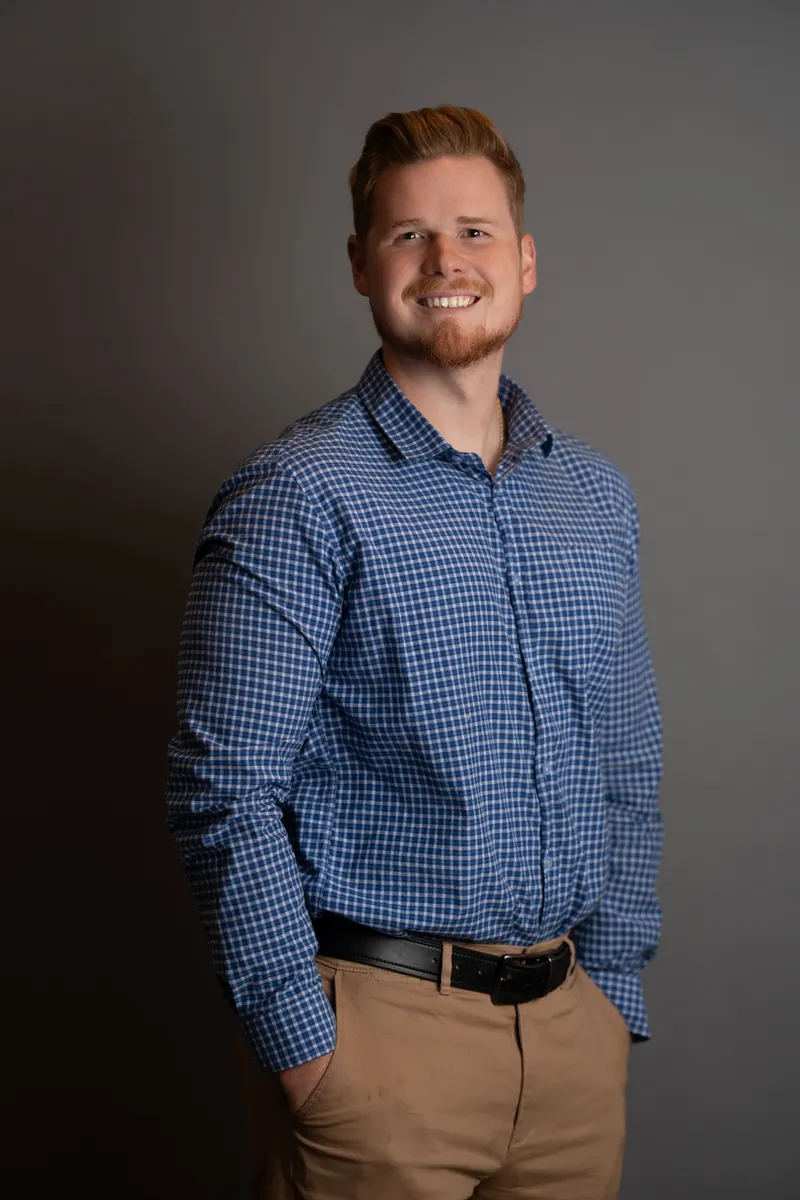 Professional headshot of man in blue checkered shirt