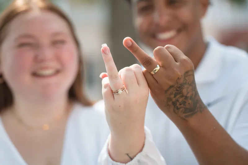 Newlyweds show off their matching wedding rings with joyful smiles after their courthouse ceremony.