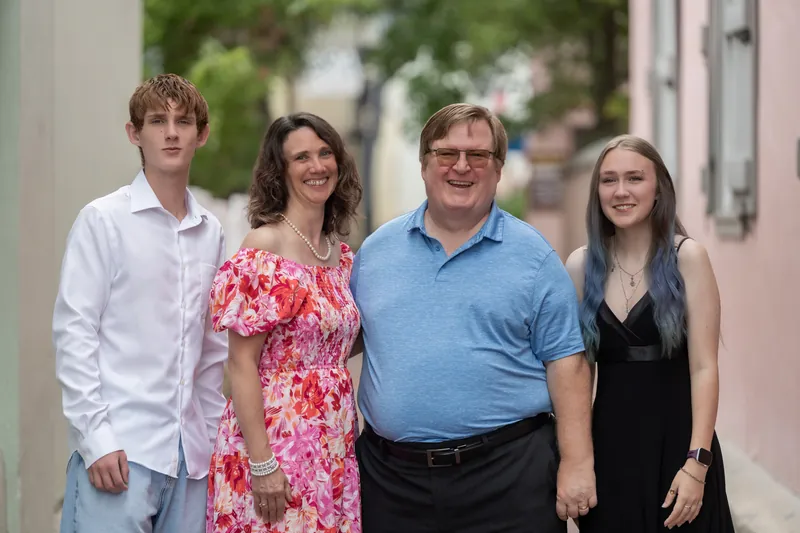 Spencer's family of four poses together on a tree-lined brick pathway in Downtown St Augustine, dressed in casual spring