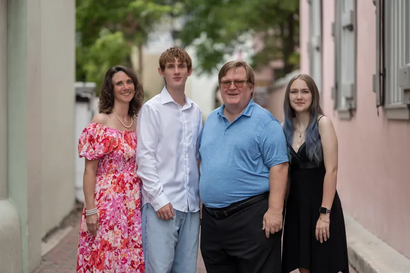 Spencer stands between his parents with his sister on a quiet brick alley in Downtown St Augustine, all four facing