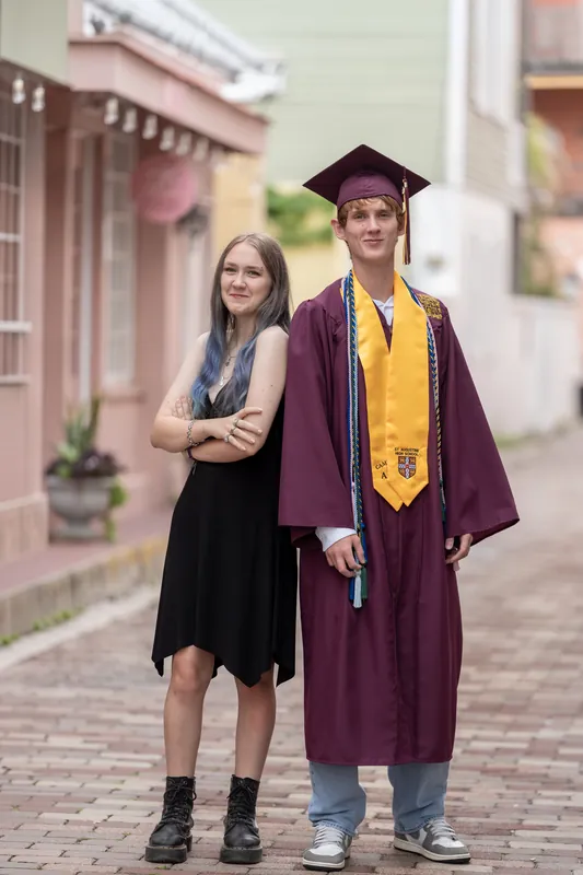 Spencer stands arm-in-arm with a female friend along a historic downtown corridor lined with pastel-colored buildings.