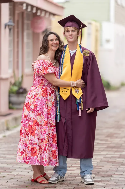 Spencer links arms with his companion in the pink dress as they pose together on the brick pathway.