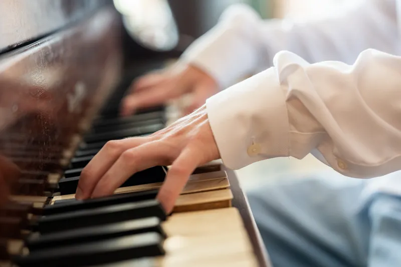 Spencer's hands rest on piano keys while wearing a white shirt in Downtown St Augustine.