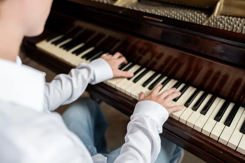 Spencer plays a grand piano in a white dress shirt during his senior session.