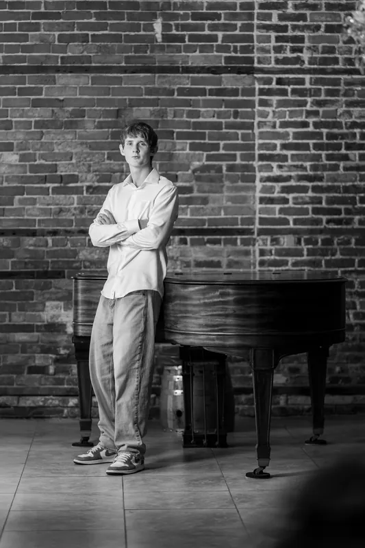 Spencer stands with arms crossed in a black-and-white portrait against an exposed brick wall in Downtown St Augustine.