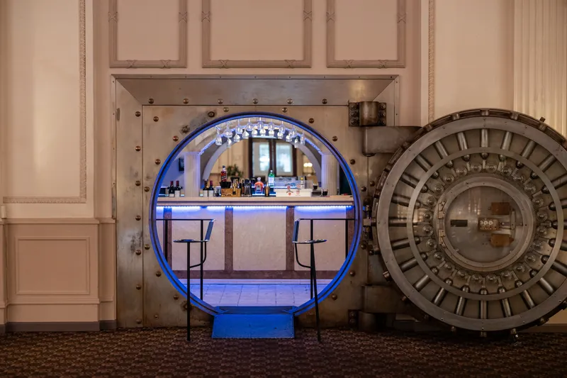 Blue neon signs frame a circular arch and ornate clockface installed as decor at The Treasury on the Plaza, St. Augustine.
