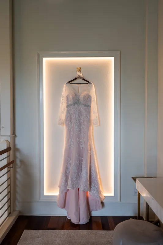 Stacy's lavender lace gown hangs on a backlit display against the wall at The Plaza Suite, St. Augustine.