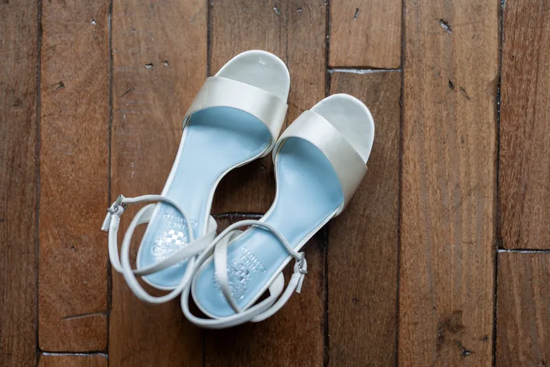 White strappy heels sit on rich wooden flooring at The Plaza Suite, St. Augustine.