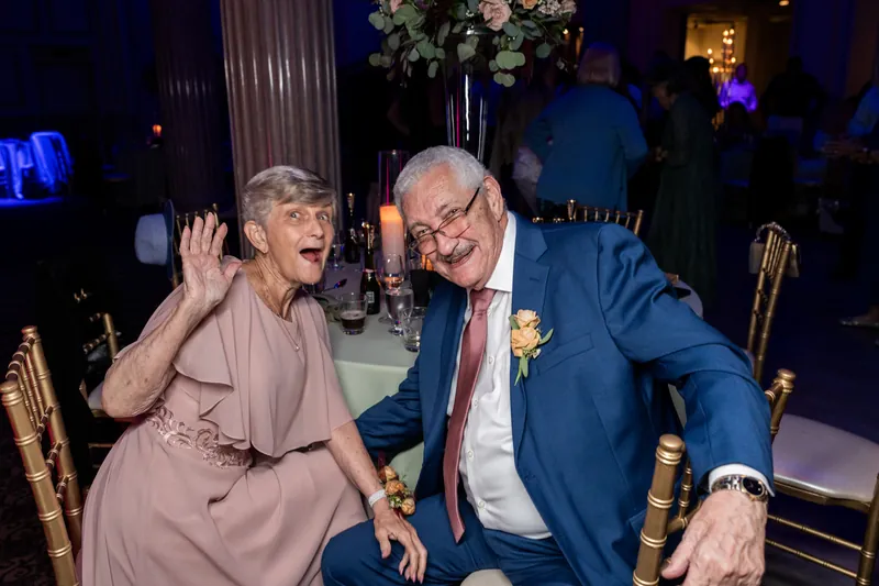 Two guests in formal attire laugh and converse during the evening celebration.
