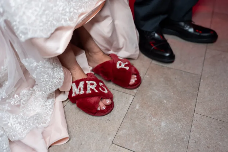 Stacy's beaded white gown and burgundy velvet slippers with "MRS" embroidered on them rest beside Dean's black dress shoes.