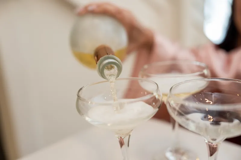 Champagne pours into a coupe glass during a toast at The Plaza Suite.