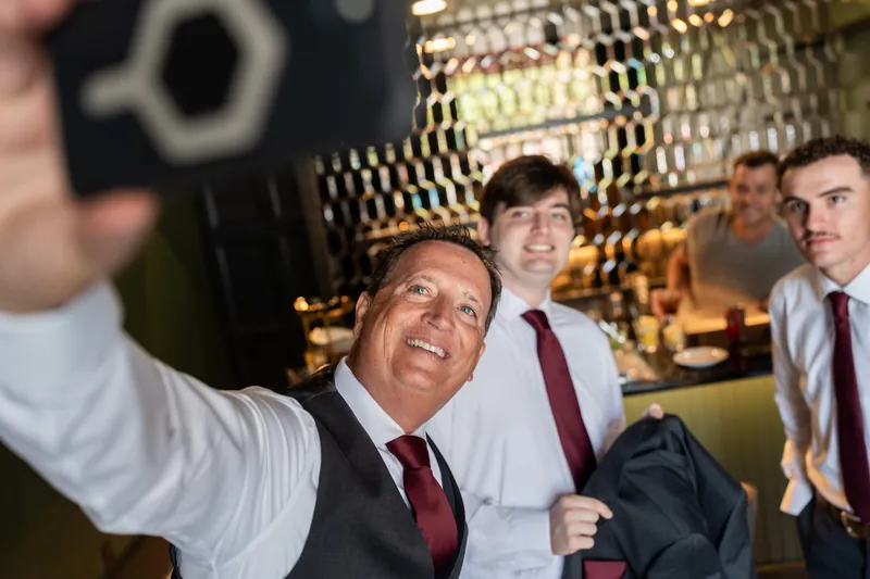 A man takes a selfie with Dean and two other guests in The Reserve's modern bar area.