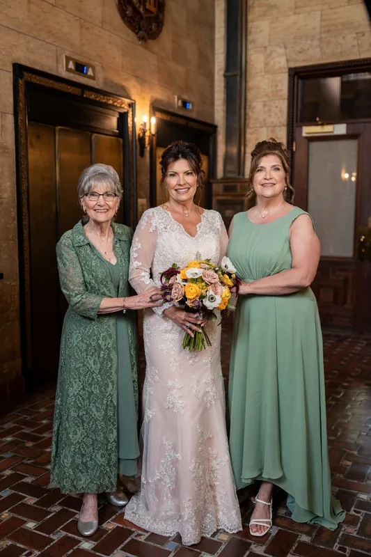 Three women pose at The Treasury on the Plaza's tiled entryway: Stacy in ivory lace flanked by guests in sage and green