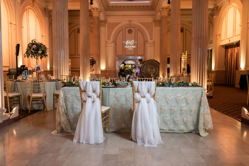 The Treasury's grand ballroom features elegant table linens, white napery, and soft golden lighting throughout the space.