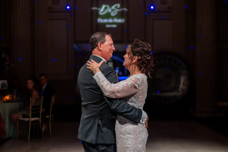 Dean and Stacy sway together on the dance floor, their connection intimate amid the evening's ambient blue lighting.