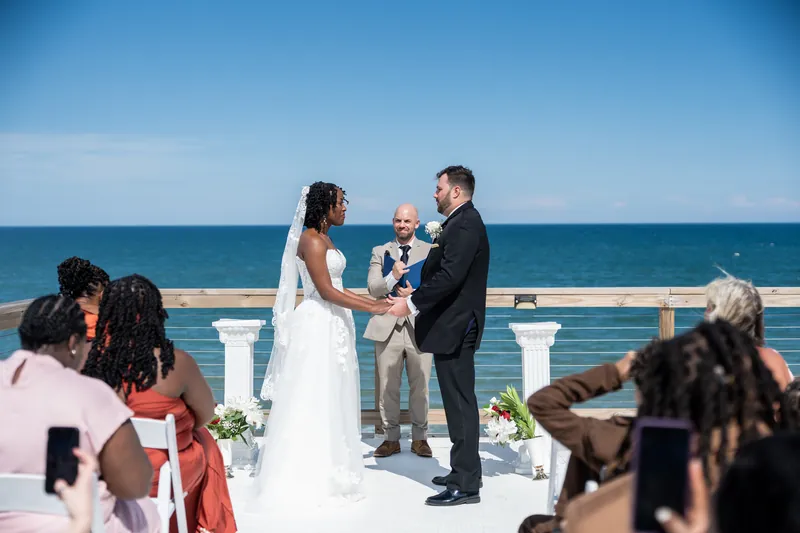 Stephen and Malika hold hands during their ceremony on a white platform above the ocean in St. Augustine.