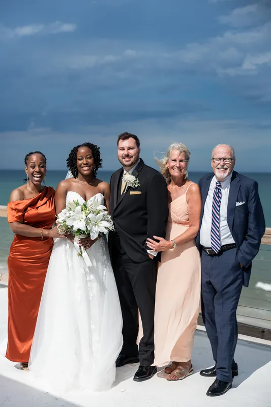 Stephen stands with four family members in formal attire for a group portrait with the sea visible behind them.