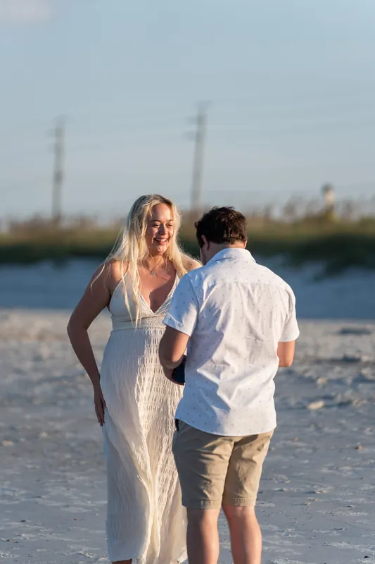 Paige reacts in surprise as Steve stands beside her on Vilano Beach, marshland stretching across the water behind them.