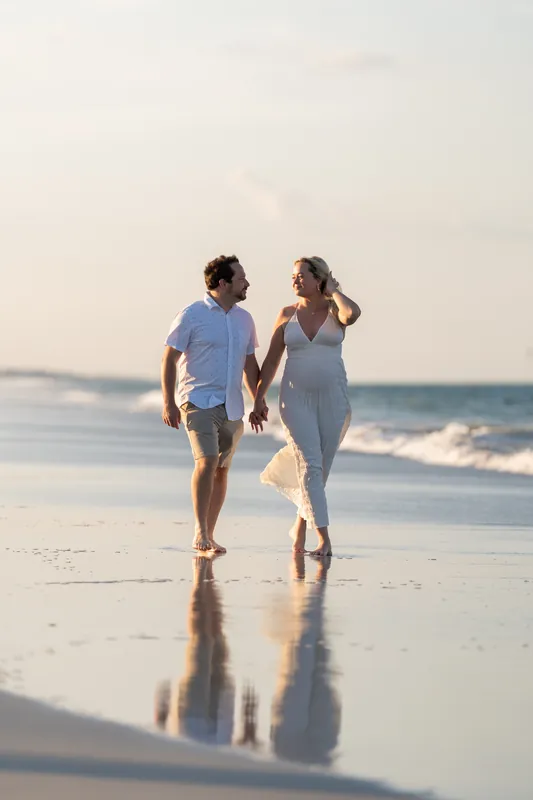 Steve and Paige walk hand in hand along wet sand at Vilano Beach as waves roll in at sunset.