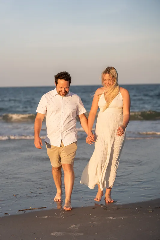 Steve and Paige stroll along the shore at Vilano Beach, walking side by side as the sun sets over the Atlantic Ocean.