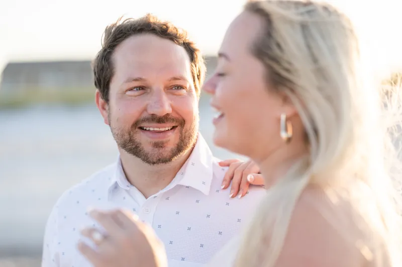 Steve grins while Paige laughs, both in white shirts with water visible behind them.
