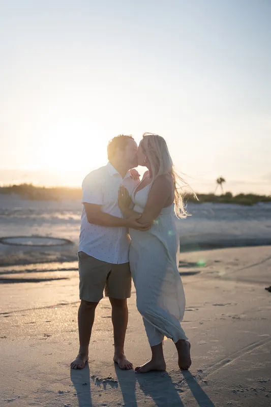 The couple holds each other as golden hour light bathes the beach around them.