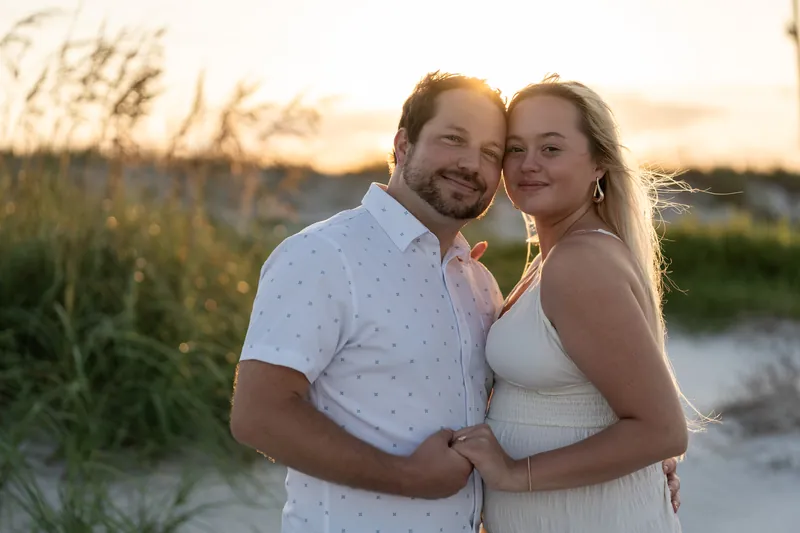 Paige rests her head against Steve's shoulder while they embrace on the sand at Vilano Beach during golden hour.