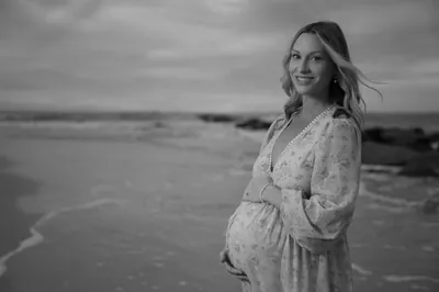 Black and white portrait of expectant mother smiling warmly at the camera on Vilano Beach.