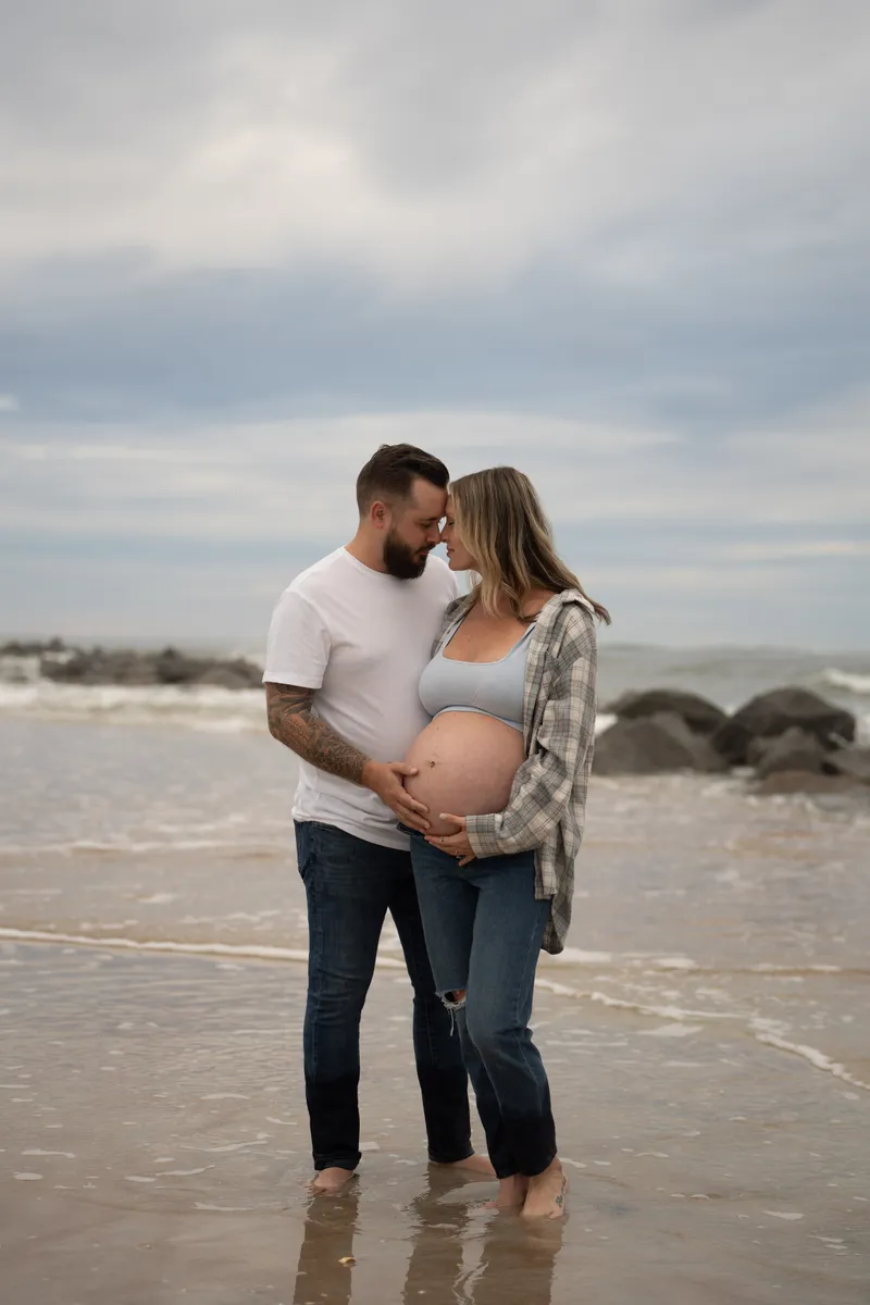 Stormi stands at the shoreline in a cream dress, gazing toward the horizon at Vilano Beach.