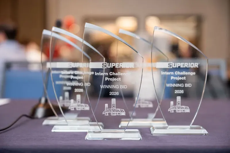 Five glass award trophies etched with "Superior" branding sit on a draped table at a professional awards ceremony.