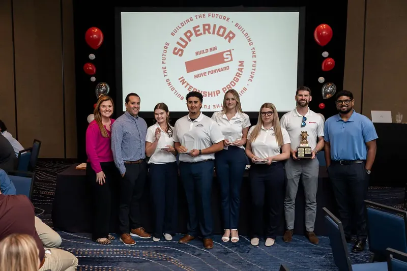 Nine team members stand in a line on stage holding awards before the Superior Party branded backdrop.