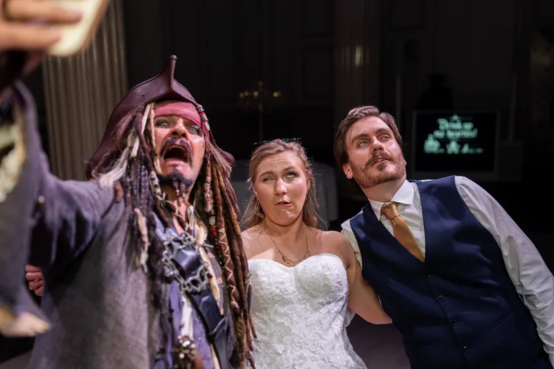 Sybil stands between a costumed character and another guest, all three smiling at The Treasury on the Plaza.