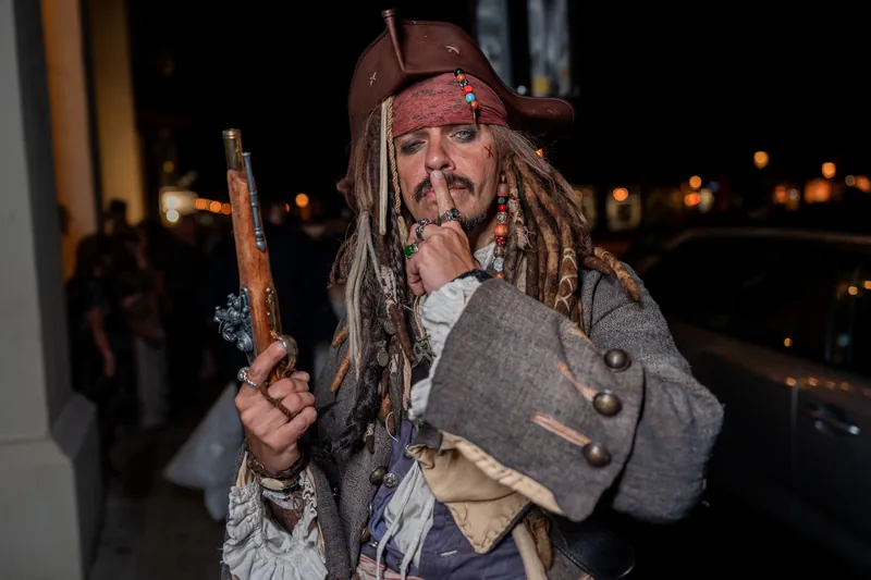 A pirate-costumed character poses on the terrace outside The Treasury on the Plaza at dusk.