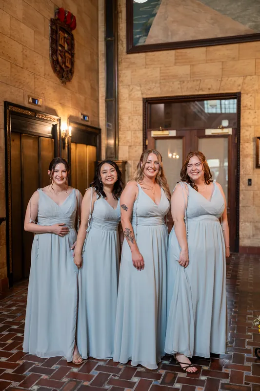 Four attendants stand together in flowing pale blue gowns inside The Treasury on the Plaza.