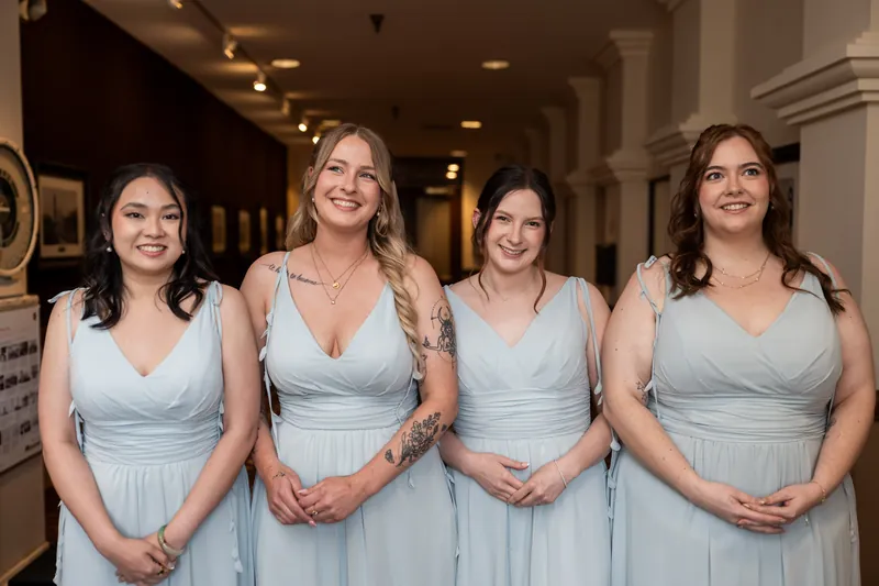 Four attendants stand shoulder-to-shoulder in matching pale blue bridesmaid dresses at The Treasury on the Plaza.