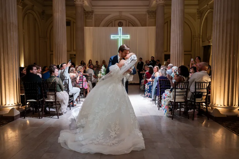 Chris dips Sybil during their first dance in the grand hall, her veil flowing as guests watch from either side.