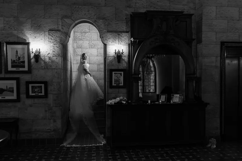 Sybil's silhouette glows against The Treasury's stone walls, her veil and dress creating a striking contrast