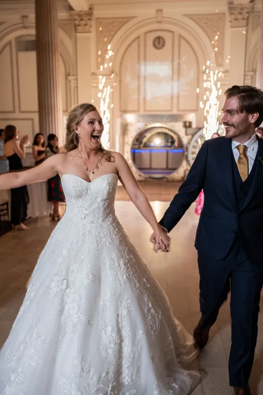 Sybil and Chris hold hands while dancing in the ornate ballroom at The Treasury on the Plaza, surrounded by guests