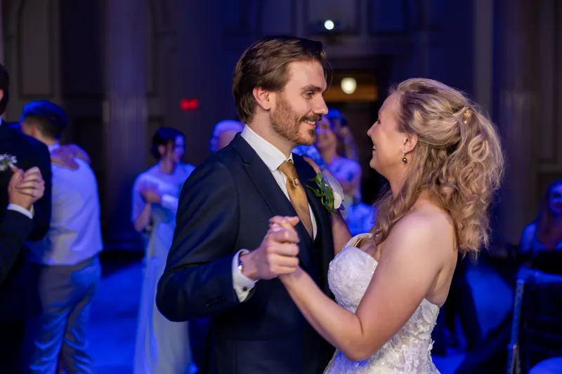 Sybil and Chris dance together under blue lighting at The Treasury on the Plaza, surrounded by wedding guests.