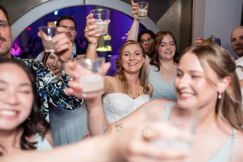 Guests raise glasses in a toast during the reception, with Sybil visible in her white dress among the crowd.