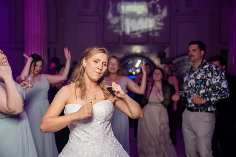 Sybil dances in her lace strapless gown at The Treasury on the Plaza while guests celebrate around her with purple uplighting