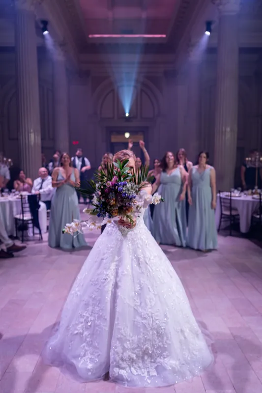 Sybil stands alone in her beaded ball gown and floral hairpiece in the grand columned ballroom at The Treasury on the Plaza.
