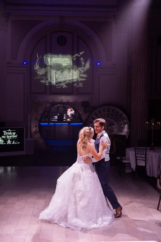 Sybil and Chris embrace on the dance floor under dramatic architectural details and projection mapping.