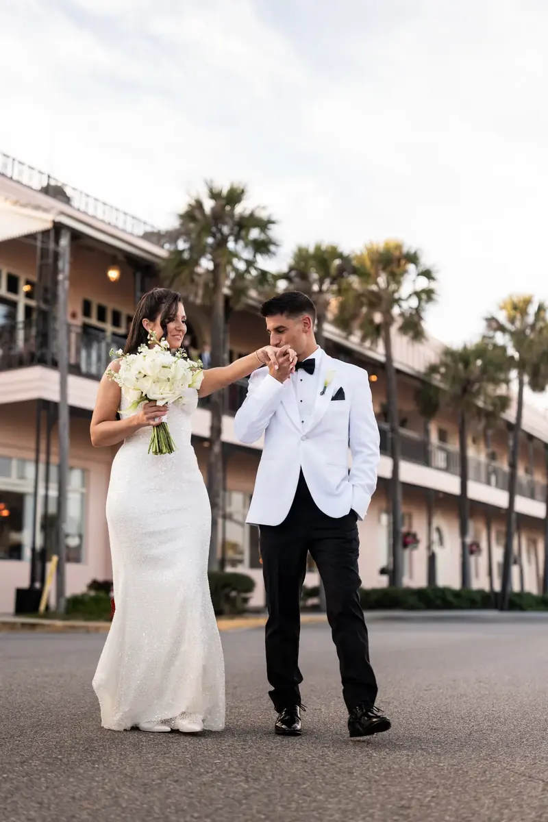 Jay in a light blue suit and Tayler in her wedding gown embrace under the arched portico at The White Room's courtyard.