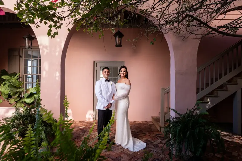 Couple portrait under arched colonnade in The White Room pink courtyard