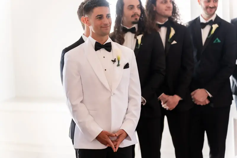 Jay waiting at altar with groomsmen in black tuxedos behind him
