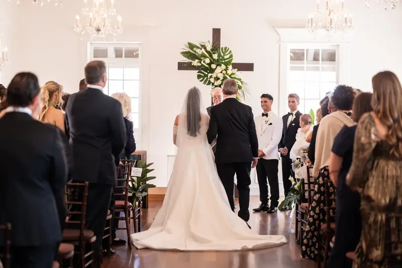 Ceremony at altar with wooden cross and monstera leaf arrangements